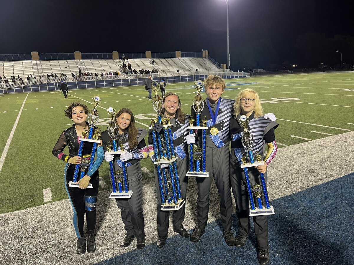High school marching band students pose with their competition trophies